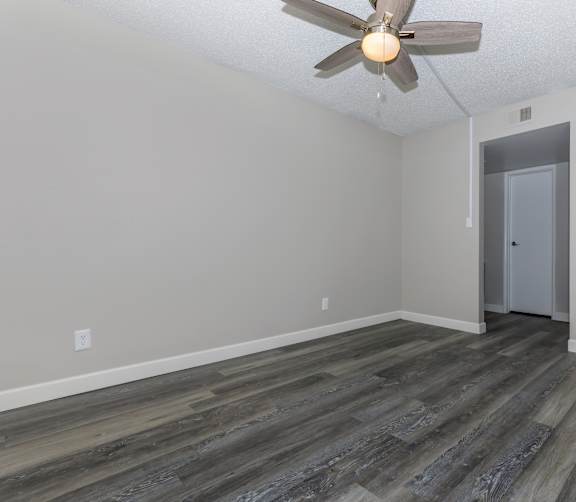 an empty living room with wood flooring and a ceiling fan