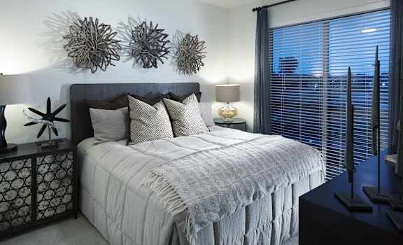 A bedroom with a bed, a ceiling fan, and a window with blinds.