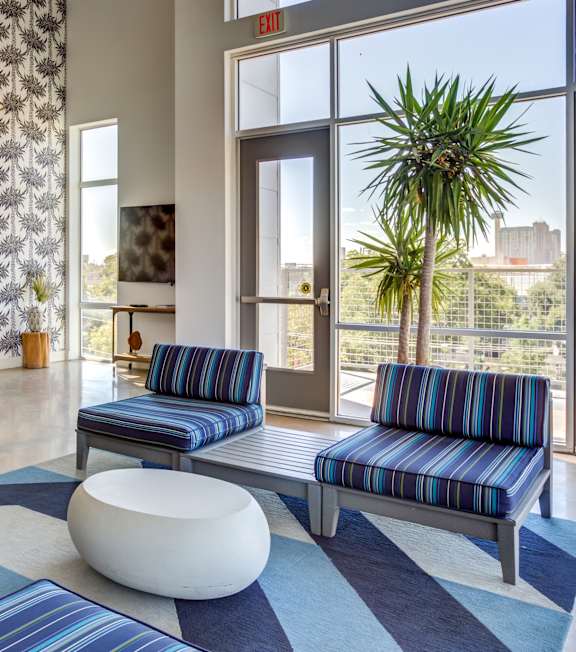 A room with blue and white striped couches and a white ottoman.