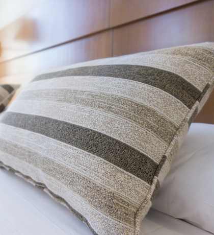 a bed with pillows and a headboard in a hotel room