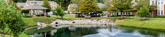a pond with a fountain in the middle of a neighborhood with houses at Carlton Park Apartment Homes, Flowood, Mississippi