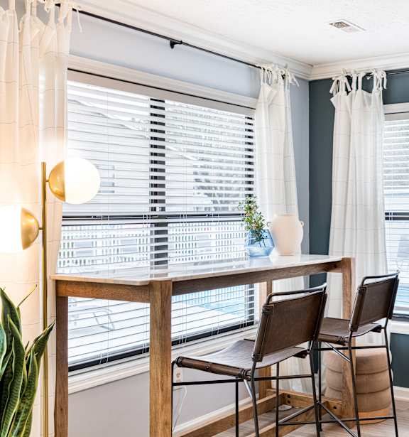 a dining room with two windows and a table with three chairs
