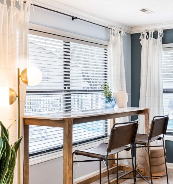 a dining room with two windows and a table with three chairs