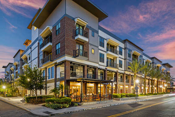 a row of apartment buildings on a city street at dusk
