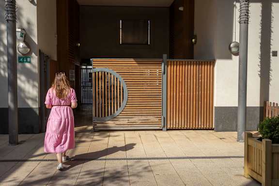 a woman in a pink dress is walking through a gate