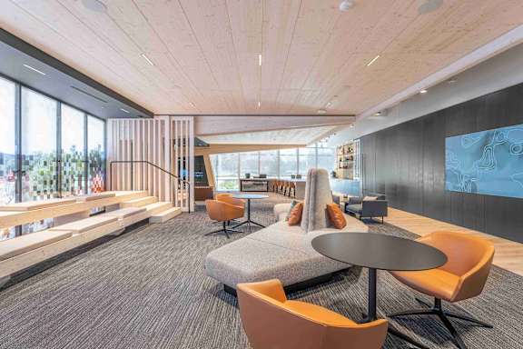 A modern office space with a wooden ceiling and a large screen on the wall.