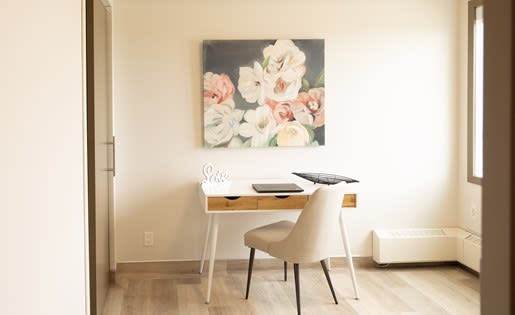 a desk and chair in a room with a painting on the wall
