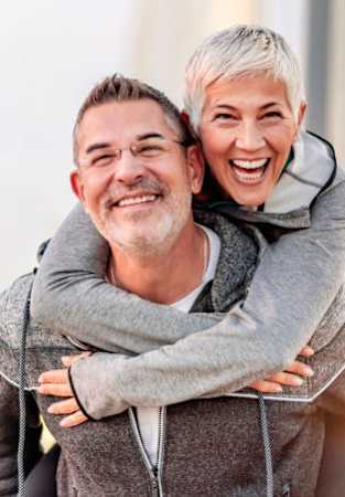 A man is giving a piggyback ride to a woman outdoors.