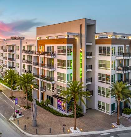 A sunset view of a street with apartment buildings on the right.