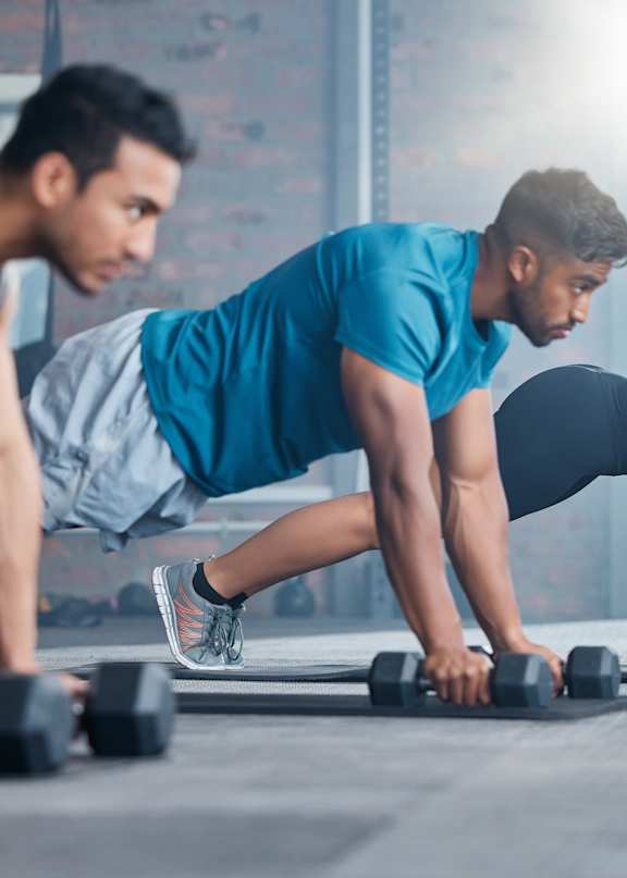 A group of people doing push-ups with dumbbells in gym at Autry at Legacy apartments in Prosper, TX.