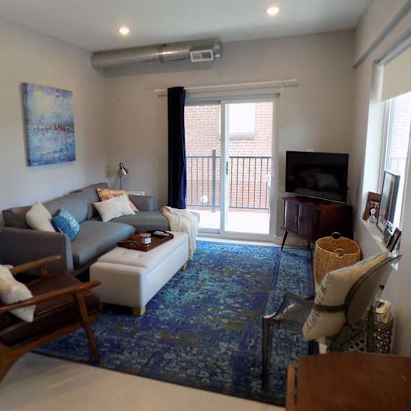 A living room with a grey couch, a coffee table, and a painting on the wall.