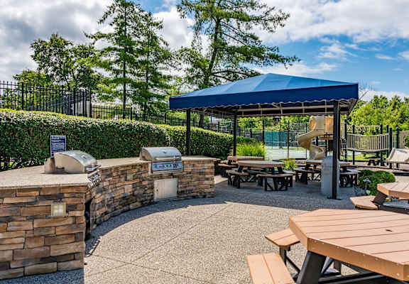 a picnic area with picnic tables and a blue roofed pavilion with a playground