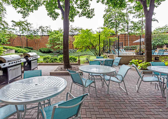 A patio with a table and chairs and a grill.