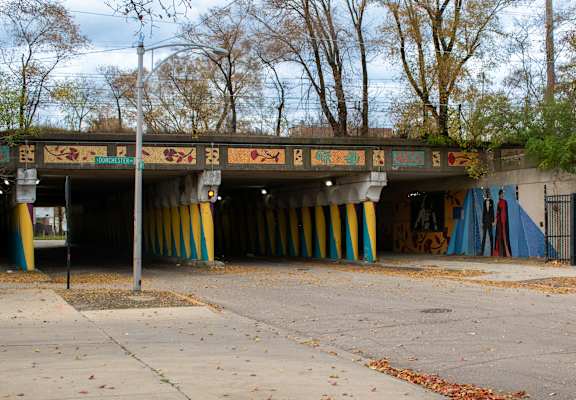 A graffiti covered bridge over a sidewalk.