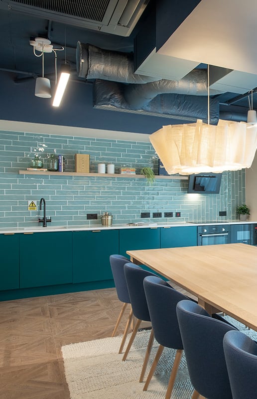 a long wooden table with blue chairs and vases