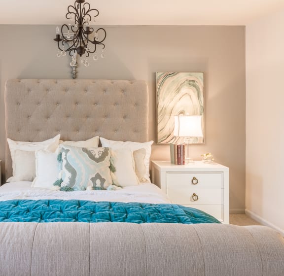 A bedroom with a large bed, a chandelier, and two nightstands with lamps. at Indian Creek Apartments, Cincinnati, OH, 45236