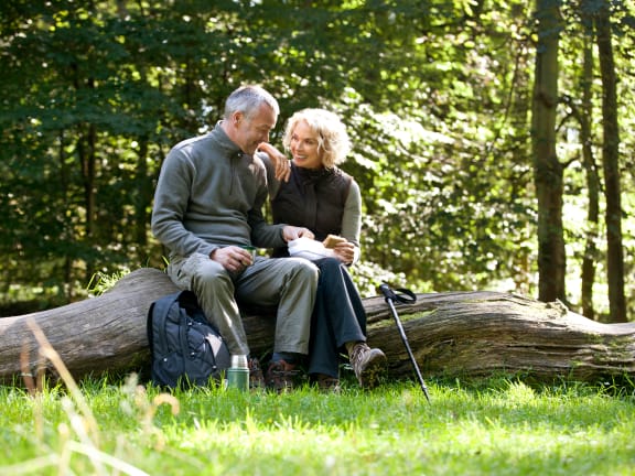 a man and a woman sitting on a log in the woods