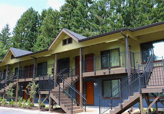 A yellow building with a balcony and stairs leading to the second floor.