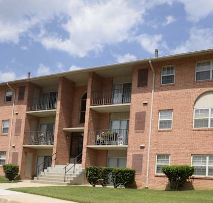 A red brick apartment building with a balcony on the second floor.