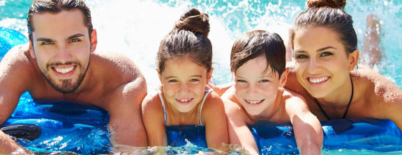 a family in the water in a swimming pool at Altis Twin Lakes Apartments, Kissimmee, FL 34744