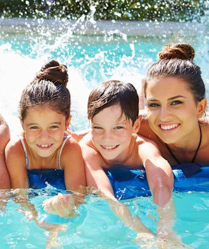 A family of four is enjoying a day in a blue pool.