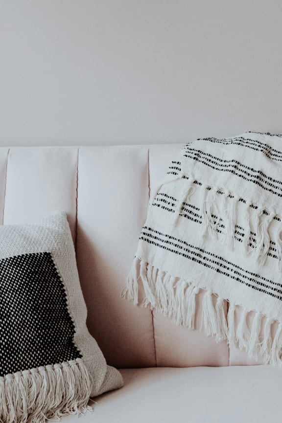 a couch with pillows and a blanket on it  at Country Oaks Apartments in Clearfield, Utah
