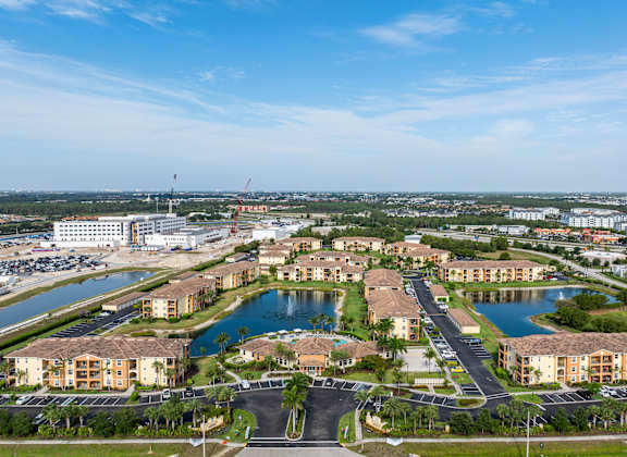 A large, well-maintained residential complex with a lake and a parking lot.