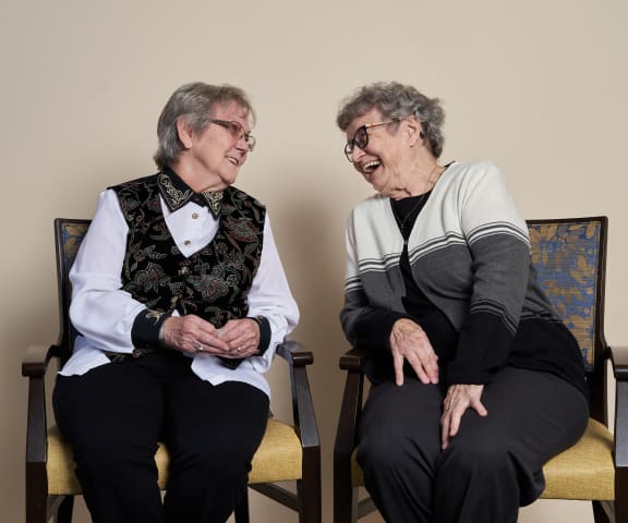 two older women sitting in chairs talking to each other