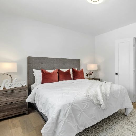 A bed with white bedding and a grey headboard with the word "Relax" written on it.
