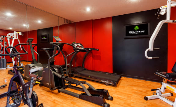 a gym with various exercise equipment on the floor and a red wall