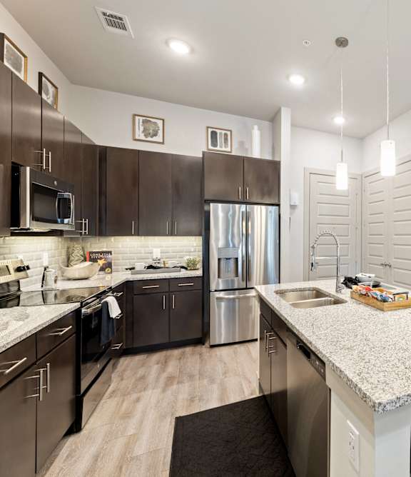 A kitchen with a white counter top and dark brown cabinets.