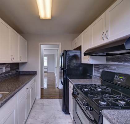 a kitchen with white cabinets and black appliances