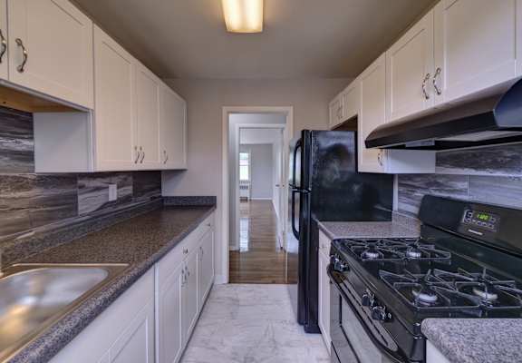 a kitchen with white cabinets and black appliances