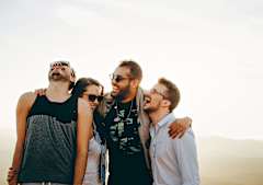 Four friends are standing together in a desert-like environment.