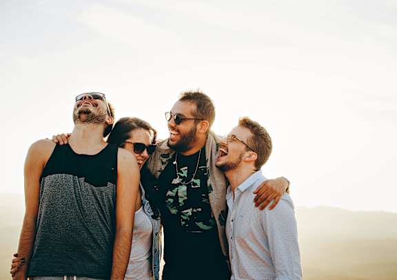 Four friends are standing together in a desert-like environment.