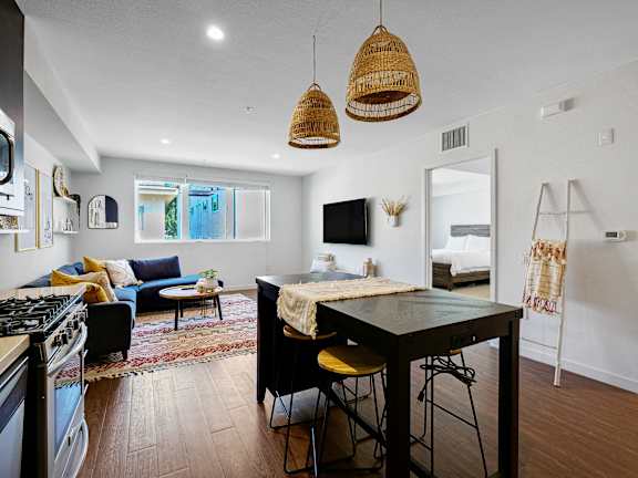 A modern kitchen with a black countertop and yellow stools.