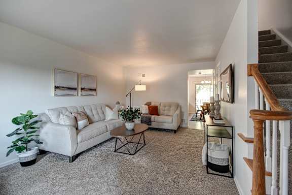 A living room with a couch, a chair, a coffee table, and a potted plant.