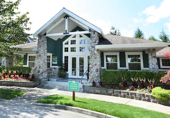 a green and white house with a green sign in front of it