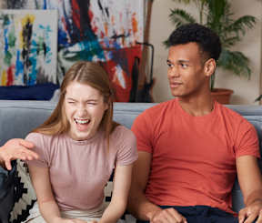 a group of young people sitting on a couch talking and laughing