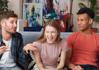 a group of young people sitting on a couch talking and laughing