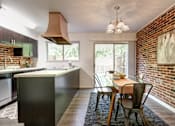 Thumbnail 3 of 26 - A kitchen with a table and chairs in front of a brick wall.