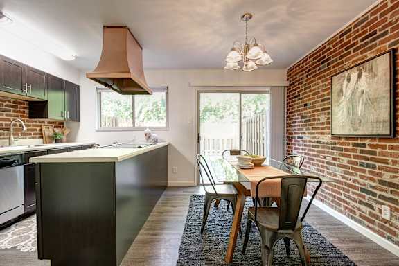 A kitchen with a table and chairs in front of a brick wall.