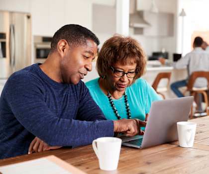 A man and a woman are looking at a laptop together.
