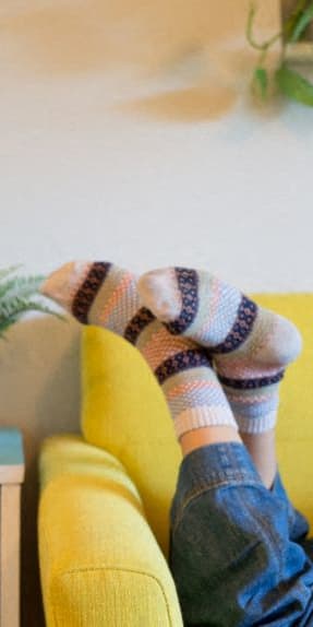 a person sitting on a yellow couch with their feet on the table
