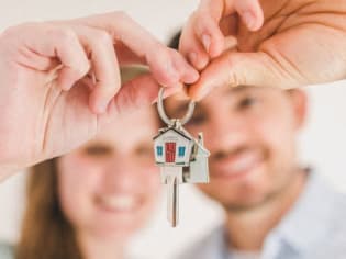a man and woman holding a house key