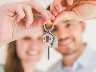 a man and woman holding a house key