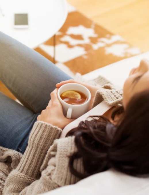 A woman is lying down holding a cup of coffee.