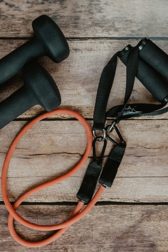 a pair of dumbbells and a jump rope on a wooden table