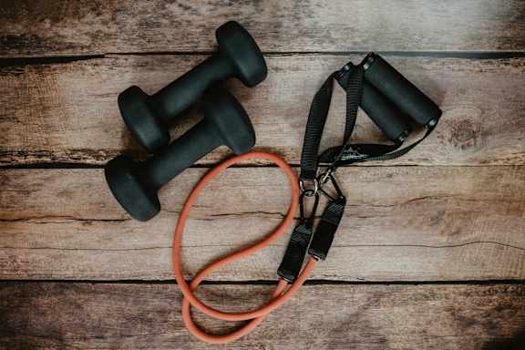Two black dumbbells and a red jump rope on a wooden surface.at Alante Homes at Spring Run, Caldwell, 83607