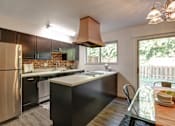 Thumbnail 4 of 26 - A kitchen with a black counter and a stainless steel refrigerator.